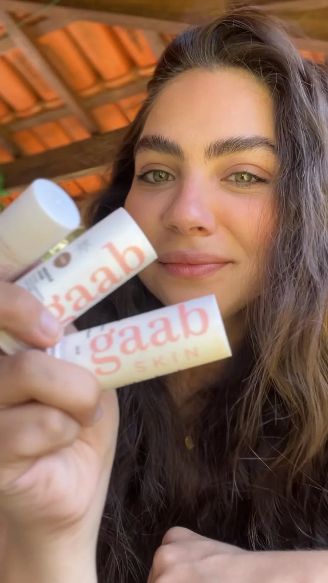 Rebeca Campano segurando os sticks de skincare da Gaab Wellness