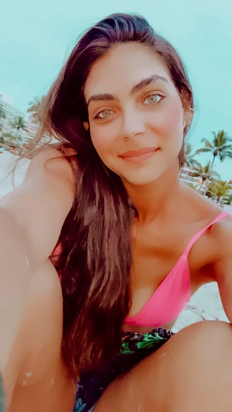 Rebeca Campano em selfie ao sol, com coqueiros ao fundo