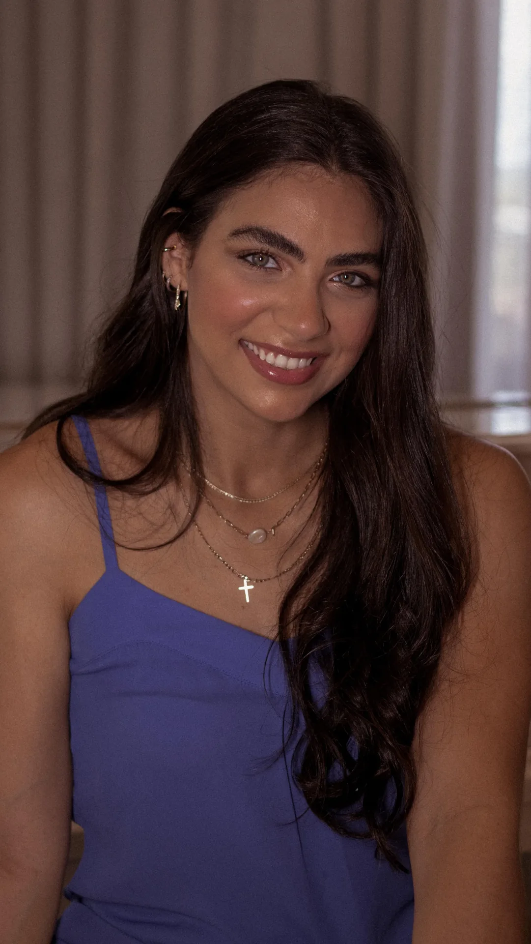 Rebeca Campano de blusa roxa e cordão com cruz, sorrindo