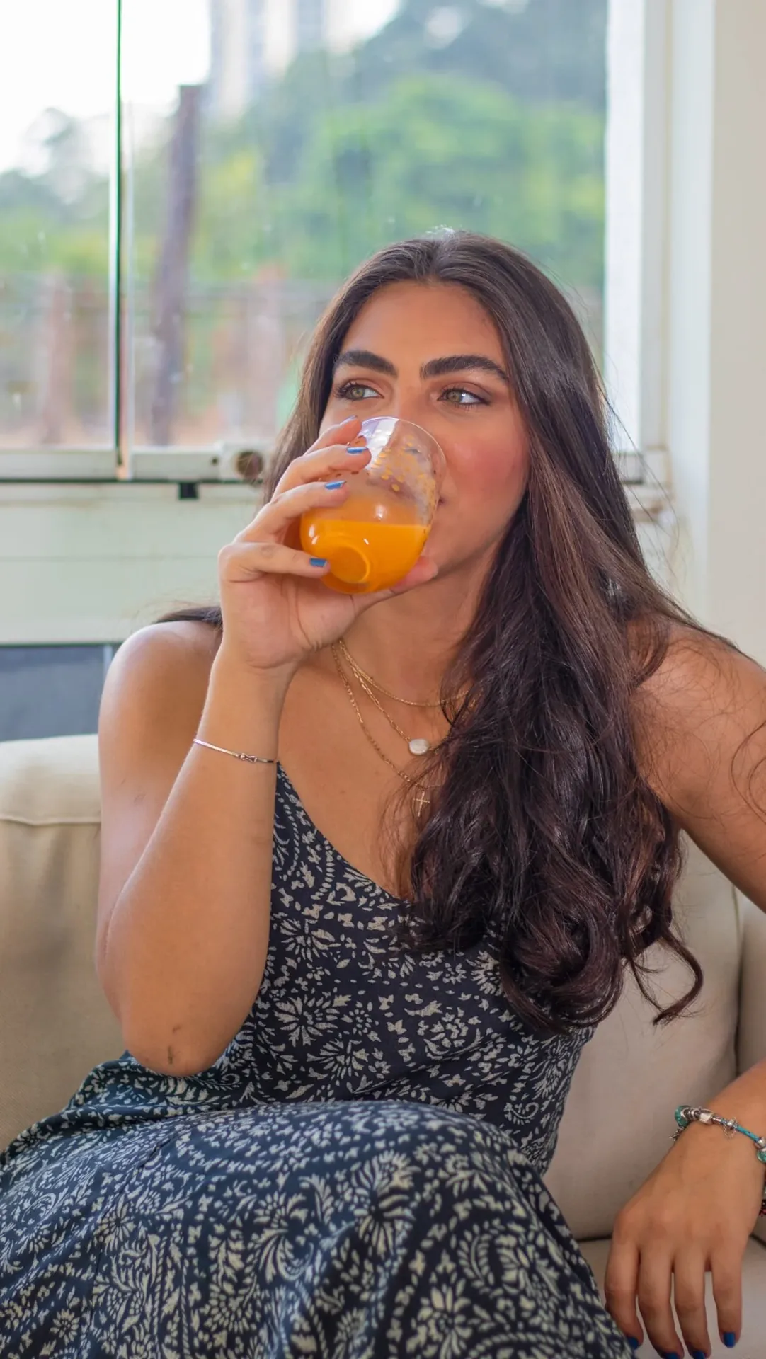 Rebeca Campano em um sofá tomando suco de laranja