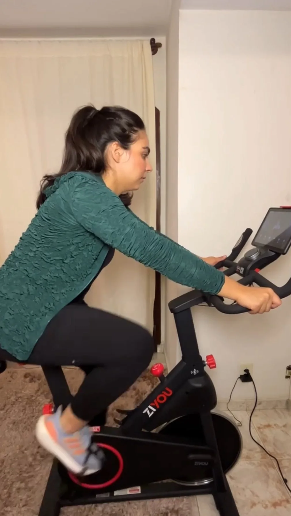 Rebeca Campano pedalando em uma bike ZiYou dentro de casa