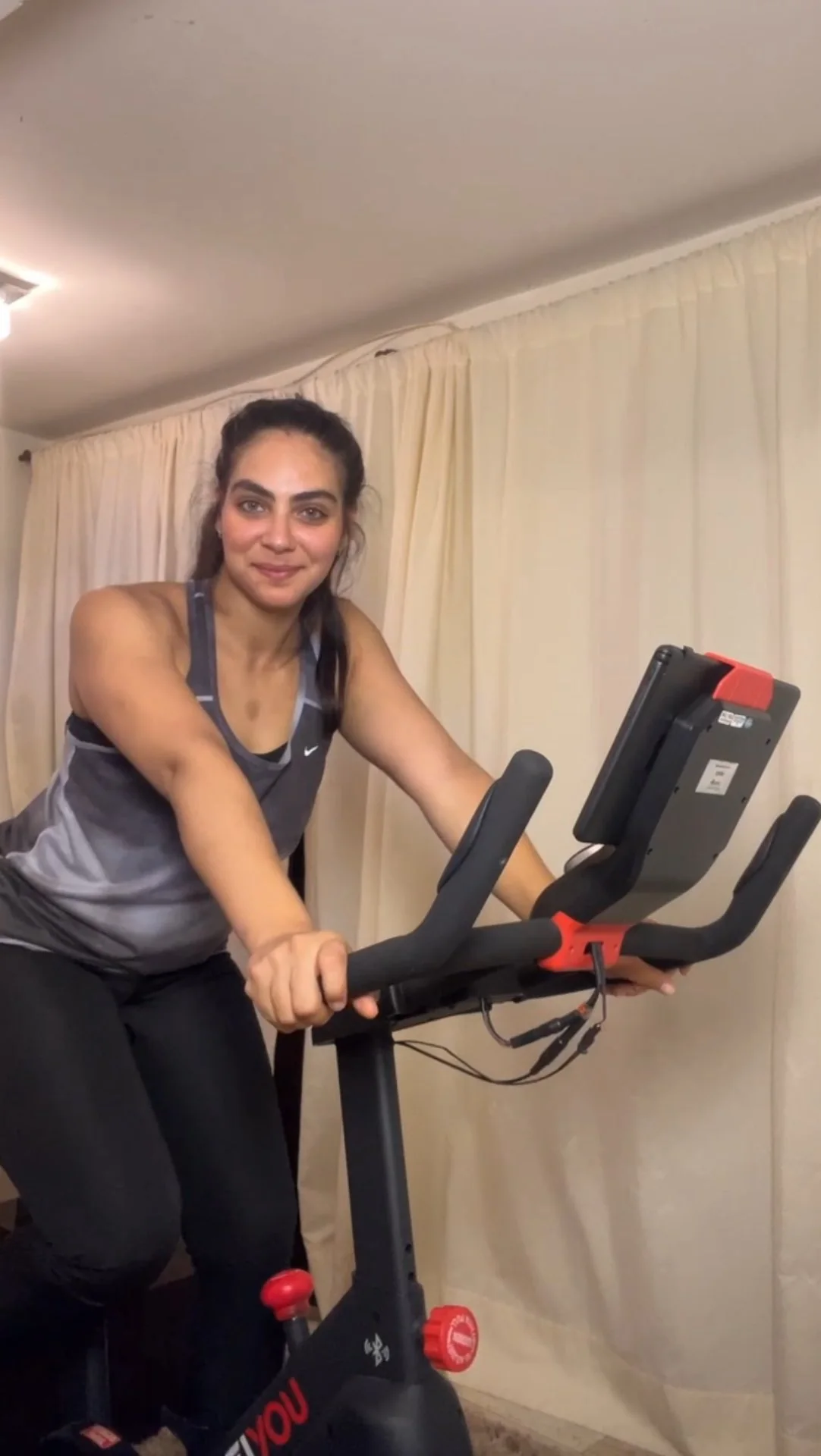 Rebeca Campano pedalando em uma bike ergométrica em casa