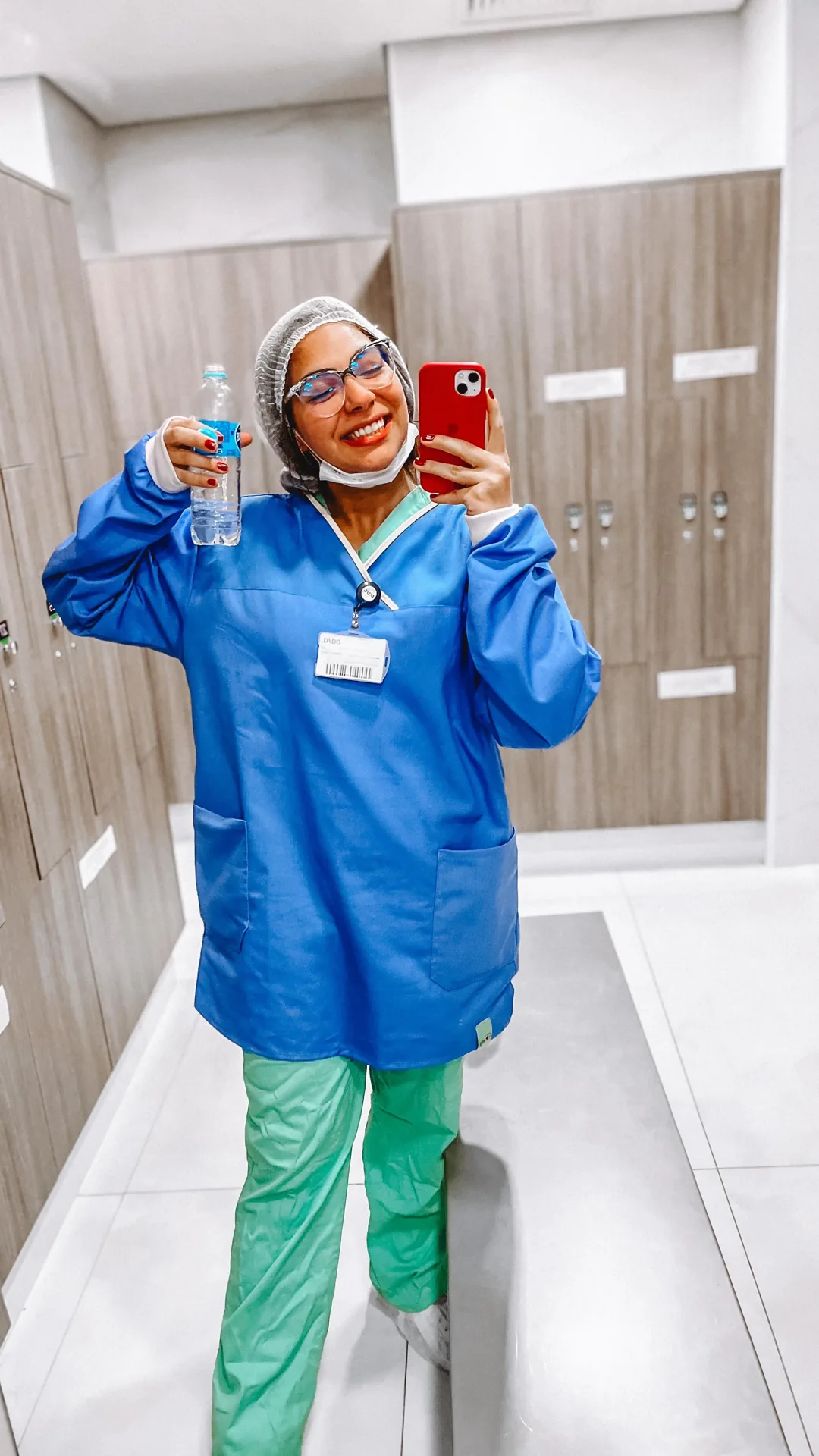 Rebeca Campano de uniforme cirúrgico azul e verde em selfie no vestiário do hospital